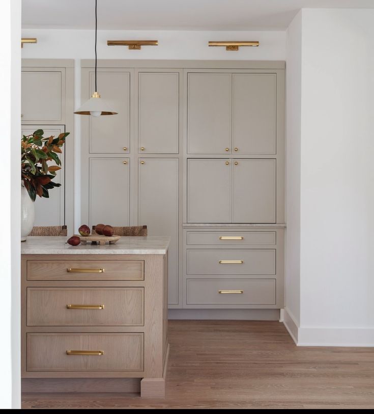 skinny shaker kitchen cabinets with light wood island and brass hardware