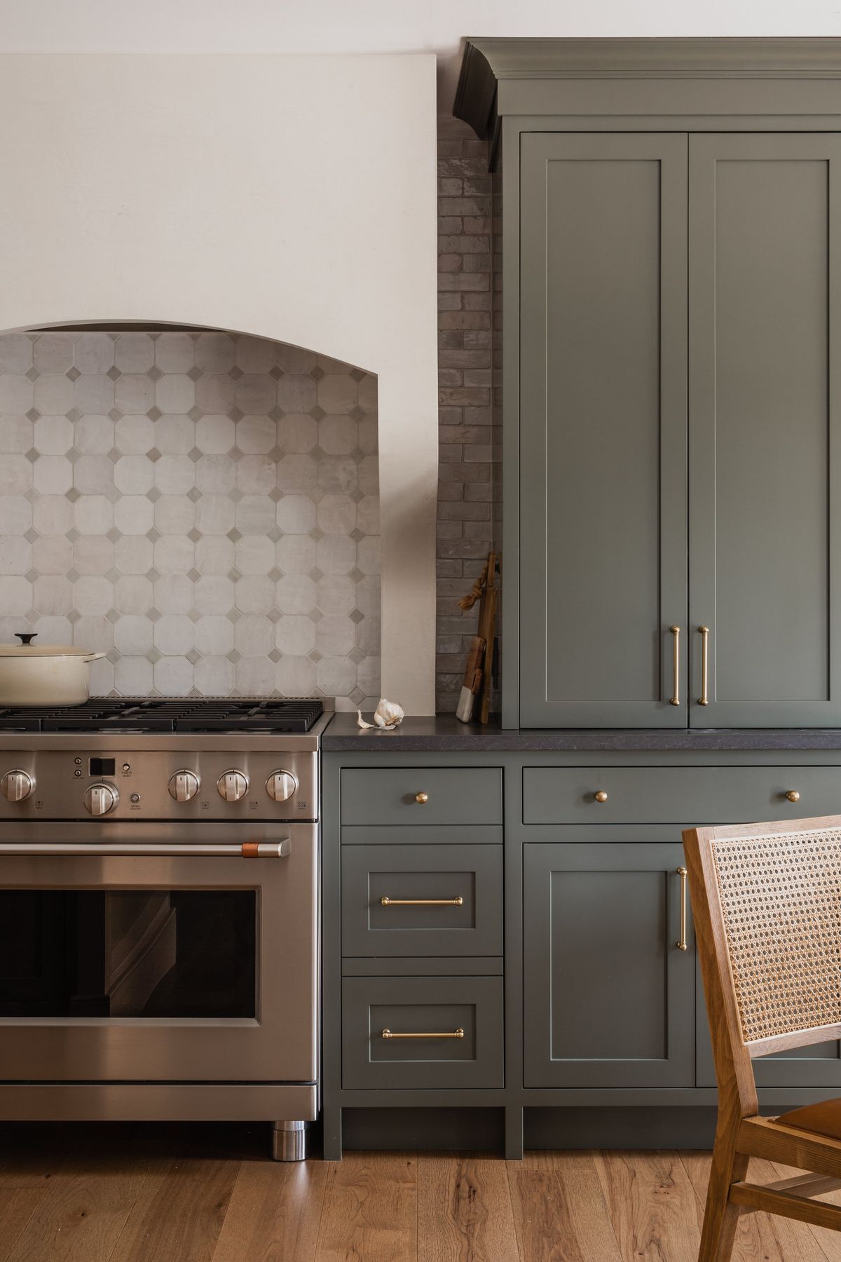 muted green shaker kitchen cabinets with arched backsplash niche and brass hardware