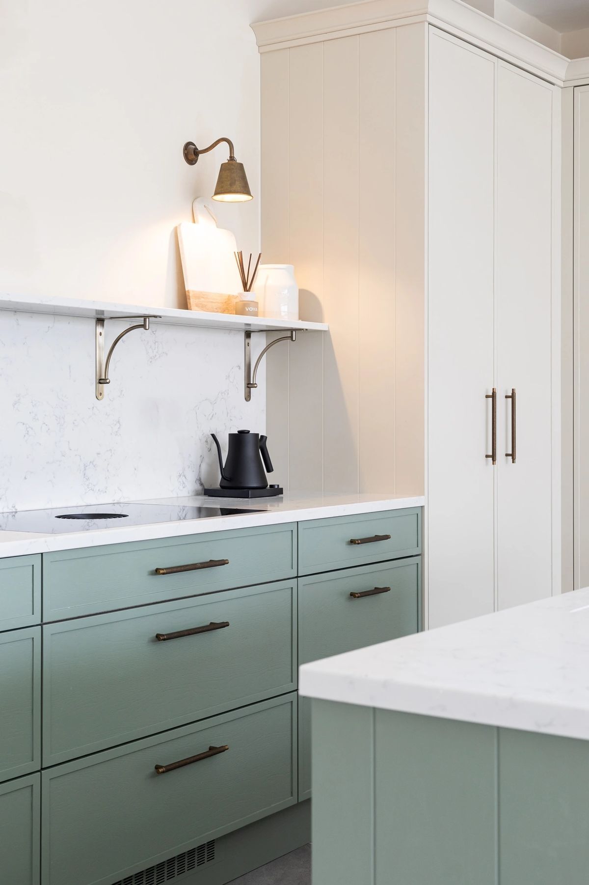 Slim shaker cabinet doors with soft green lower cabinets, white upper cabinets, vertical panel detail, and brass hardware in modern kitchen.