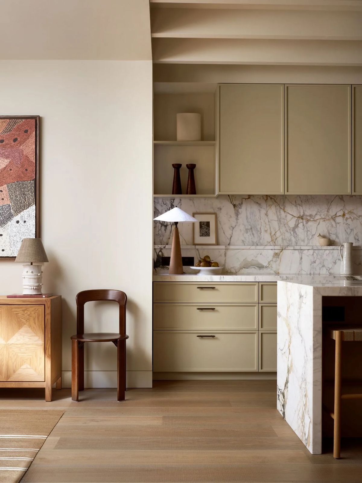 Slim shaker cabinets in warm buttercream tone with marble backsplash, wood accents, and modern neutral kitchen design.