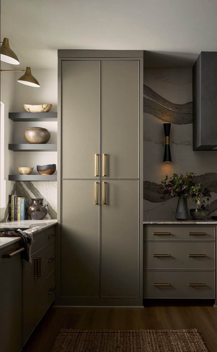 Deep taupe slim shaker cabinets with brass handles, open shelving, and dramatic stone backsplash in a modern kitchen.