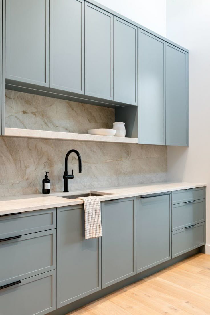 Dusty blue slim shaker cabinet doors with black hardware, marble backsplash, and modern minimalist kitchen design.