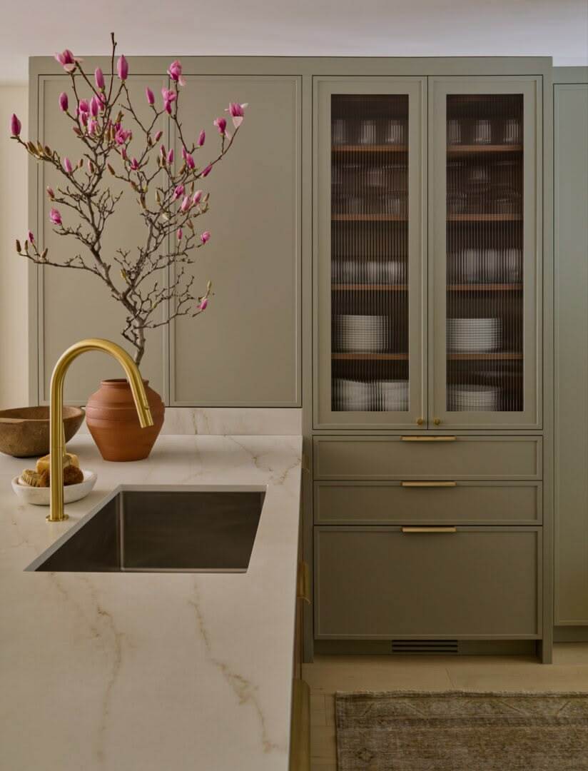 Slim shaker cabinets with reeded glass doors, sage green cabinetry, brass hardware, and modern kitchen design.