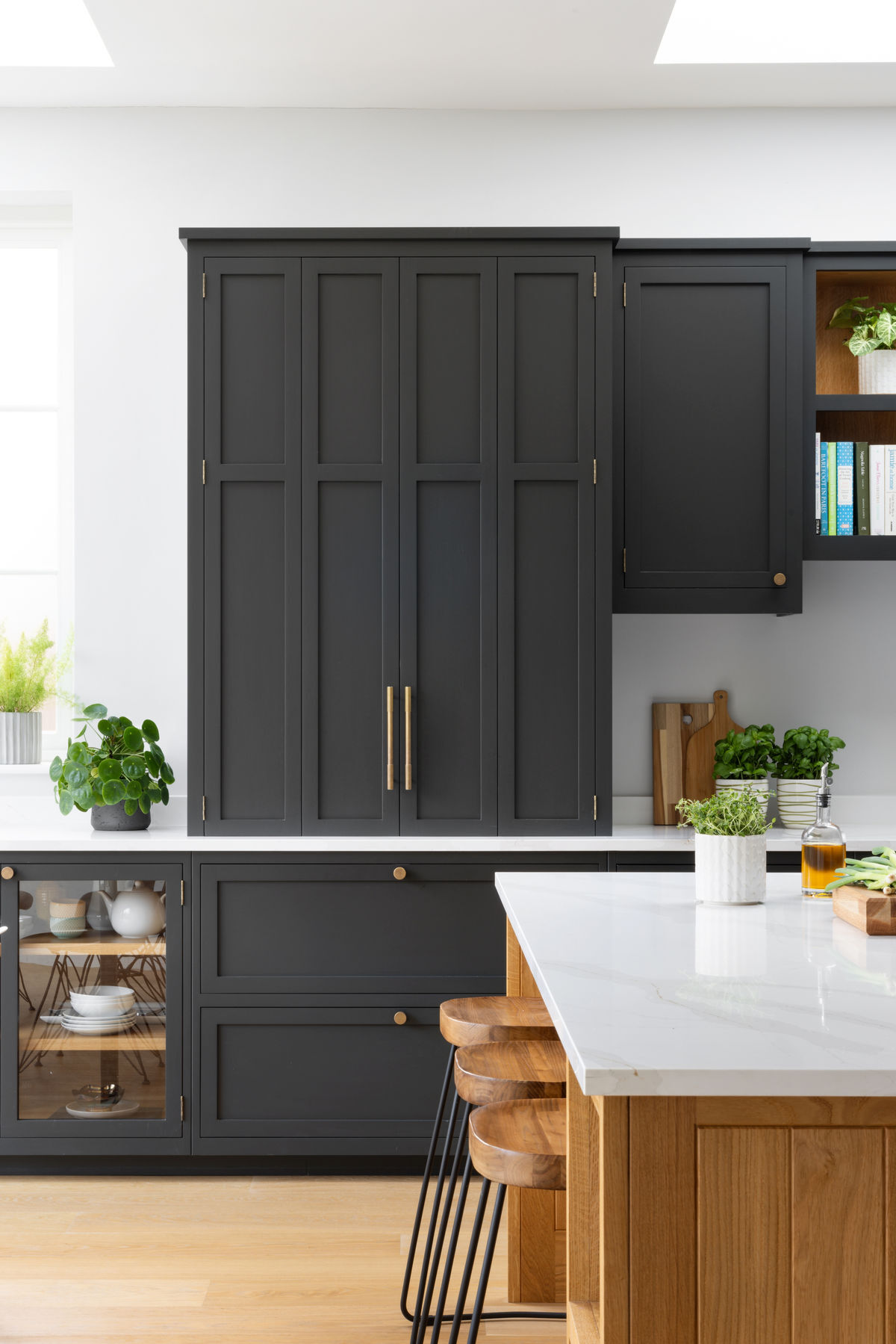 black shaker kitchen cabinets with white countertops and wood island seating
