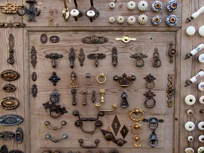 A cabinet door covered in knobs and handles as a display.