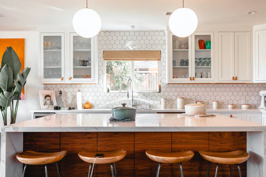 A large, bright kitchen with white shaker cabinets that have glass panels.