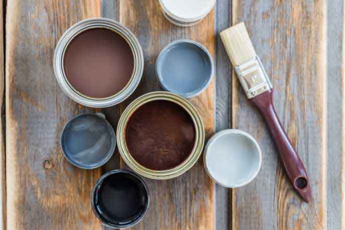 A paint brush sitting next to open paint cans seen from above.