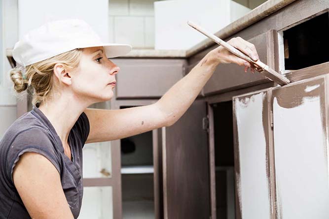 A person painting cabinet brown.