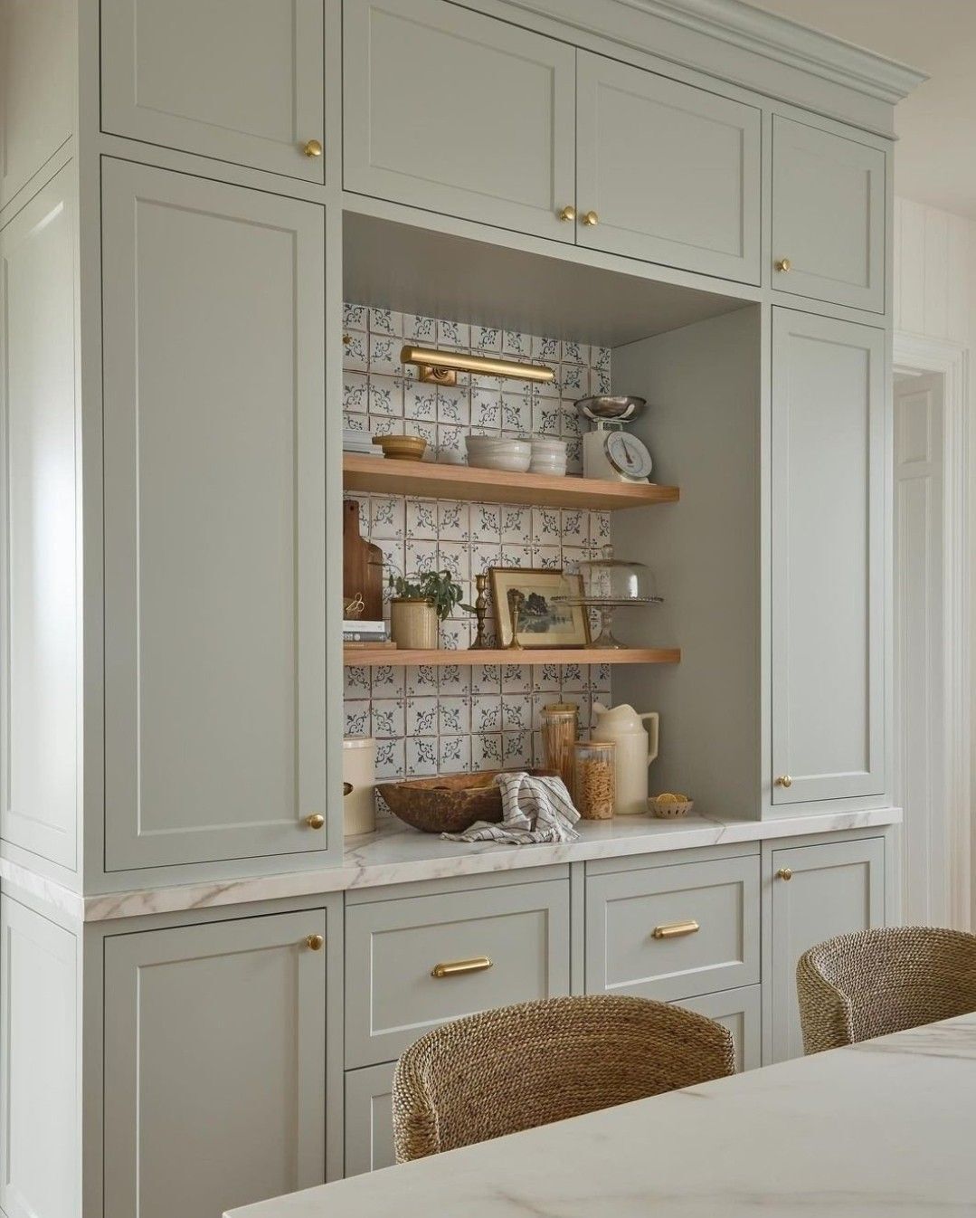 seafoam green shaker cabinets with tiled niche and open wood shelving in a cottage kitchen