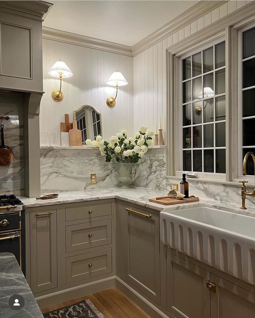 taupe shaker cabinets with beadboard walls marble backsplash and farmhouse sink in a cottage kitchen