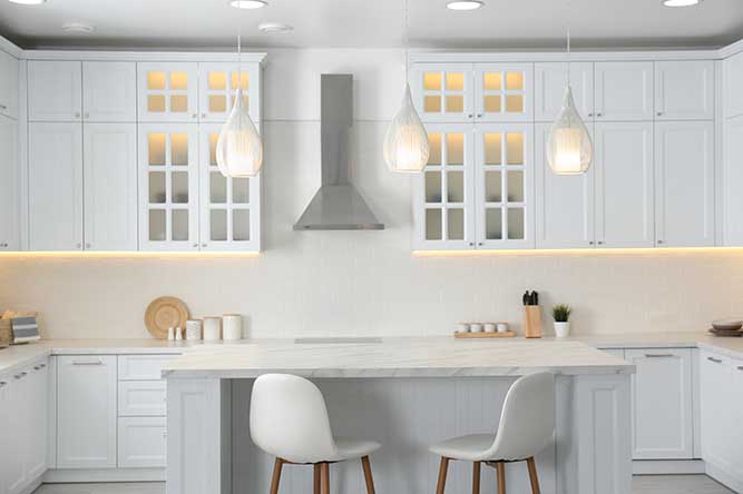A kitchen with white shaker cabinets and glass front shaker cabinets.