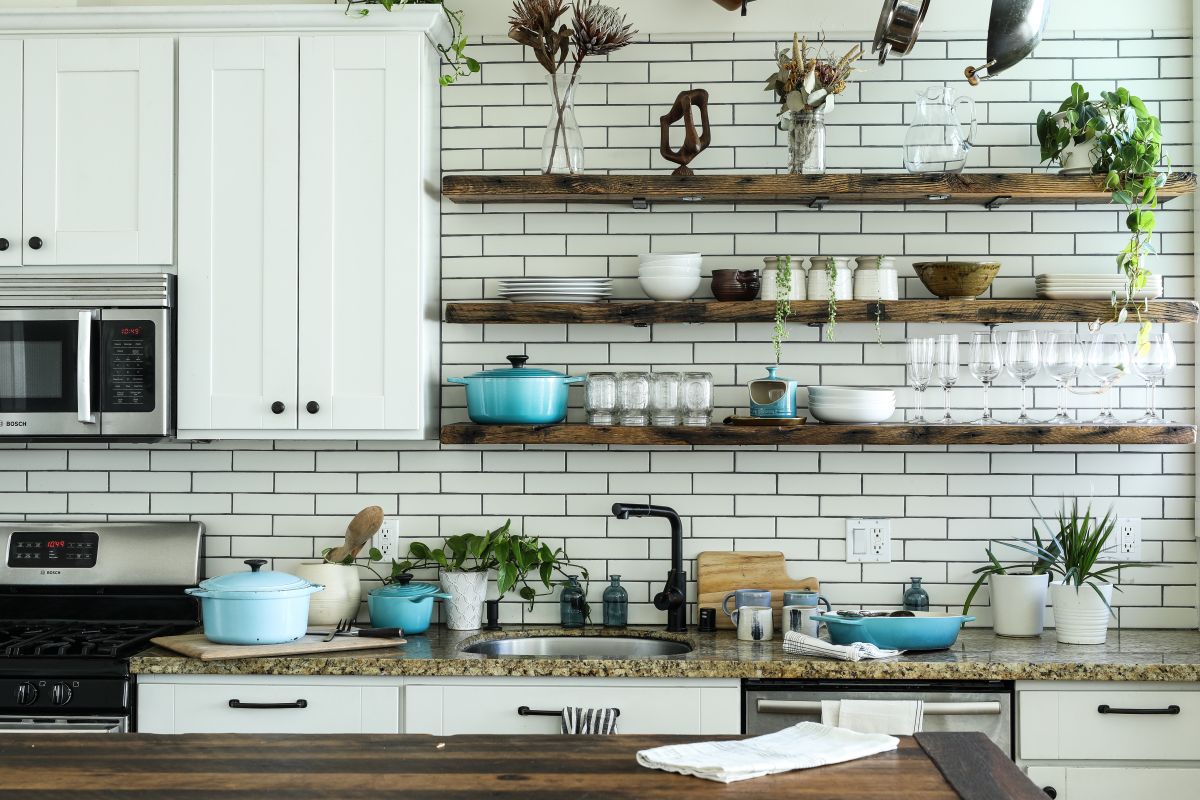 A kitchen with bright white shaker style cabinet and open shelves.