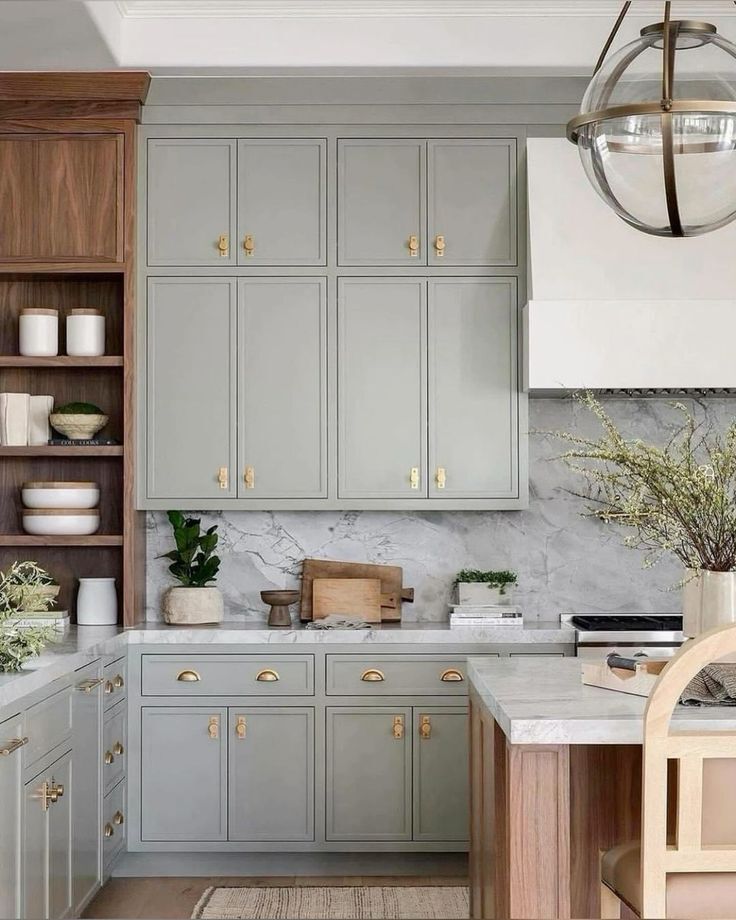 Soft sage green slim shaker cabinets with brass hardware, marble backsplash, and warm wood accents.