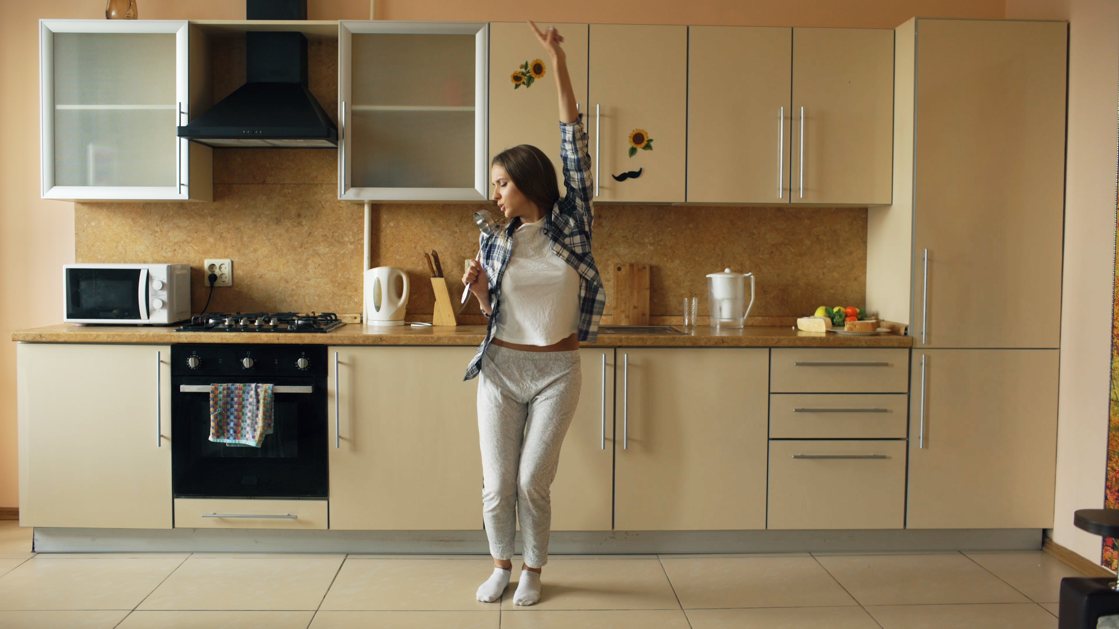 A person dancing in their kitchen, which is filled with natural light.