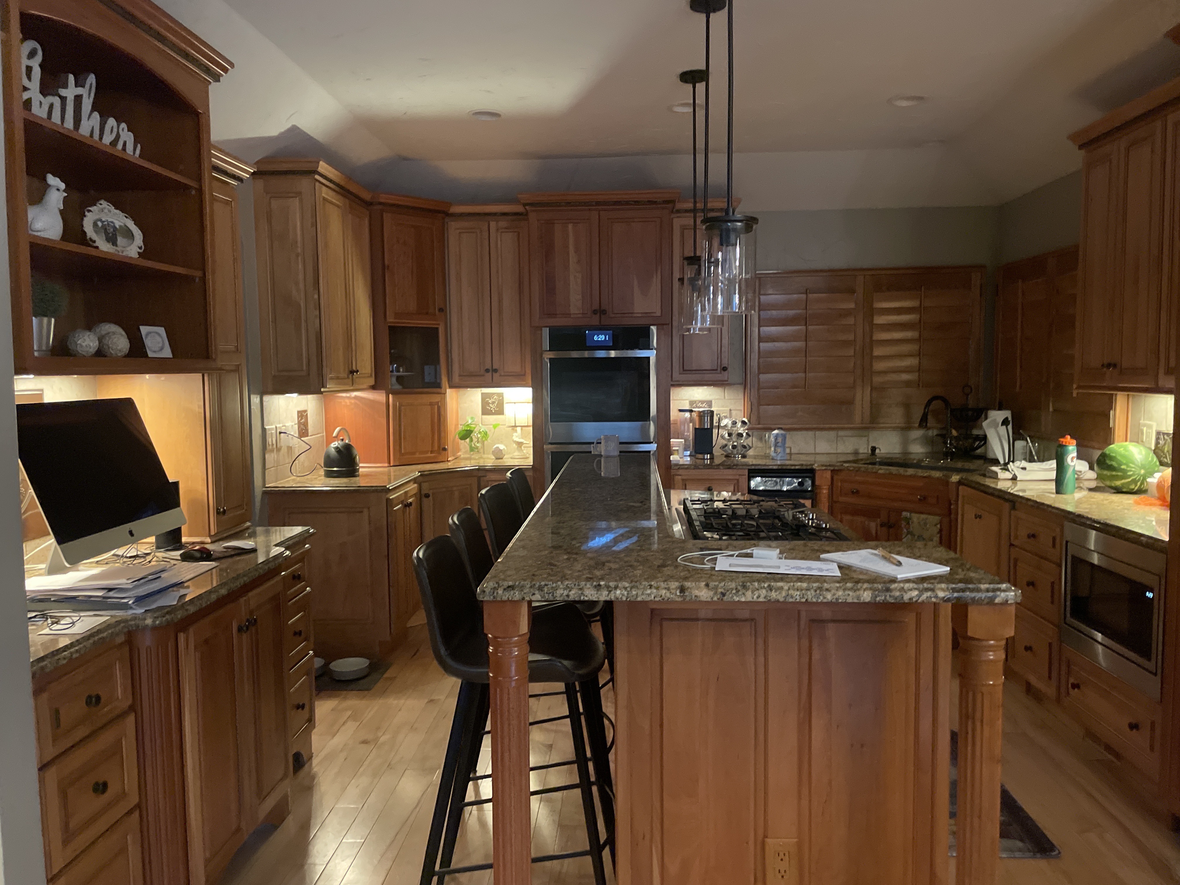 Before photo of an outdated oak kitchen prior to DIY cabinet door replacement featuring traditional wood cabinetry, granite countertops, and raised panel cabinet doors before a modern Shaker kitchen makeover.