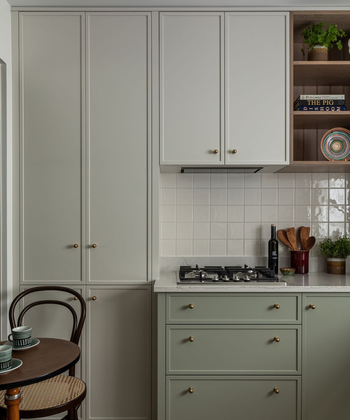 Slim shaker cabinet doors in soft green with neutral upper cabinets and brass hardware in a modern kitchen design.