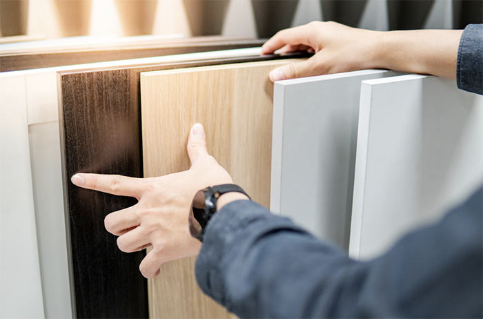 A pair of hands selecting cabinet doors. 