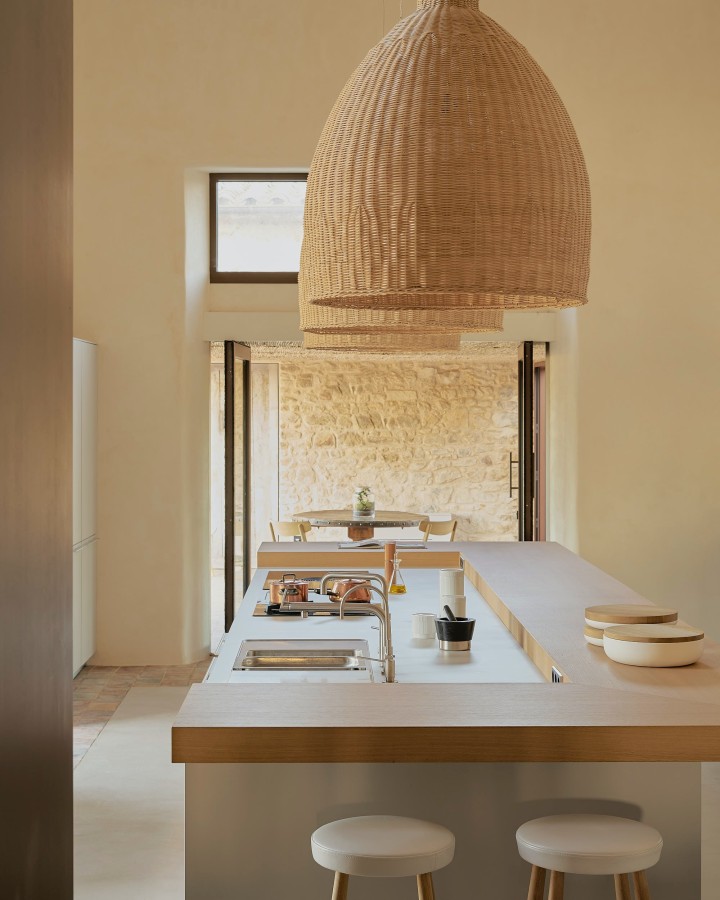 A kitchen island with a hot water tap and large hanging lights.