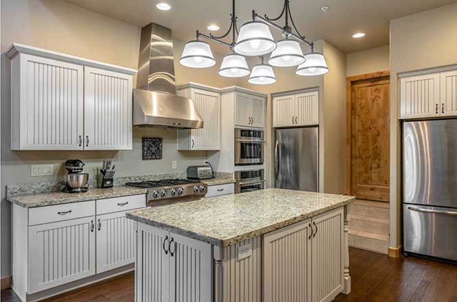 A transitional kitchen with bead board cabinets and stainless steel appliances.