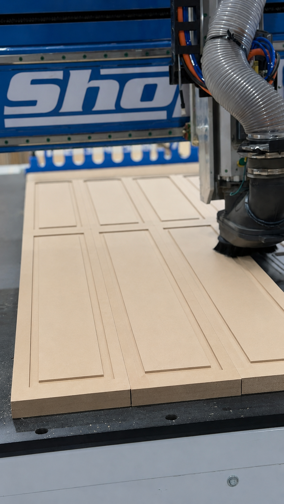 CNC router machining one-piece MDF shaker cabinet doors in a cabinet manufacturing facility.
