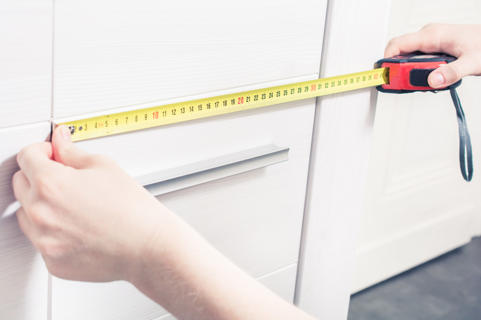 A person measuring the cabinet face.