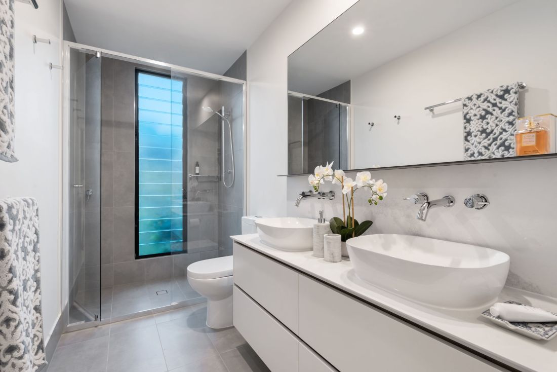 A modern bathroom with bright white cabinets and vanity.