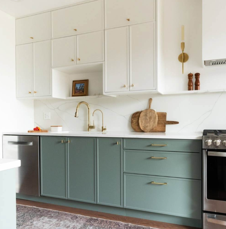 modern kitchen with sage green shaker cabinets, white upper cabinets, brass hardware, and marble backsplash