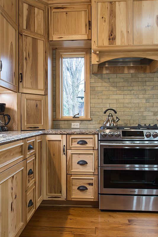 Natural Rustic Hickory Kitchen Cabinets with Neutral Tile Backsplash Natural rustic hickory kitchen cabinets with black hardware, granite countertops, and a neutral tile backsplash.