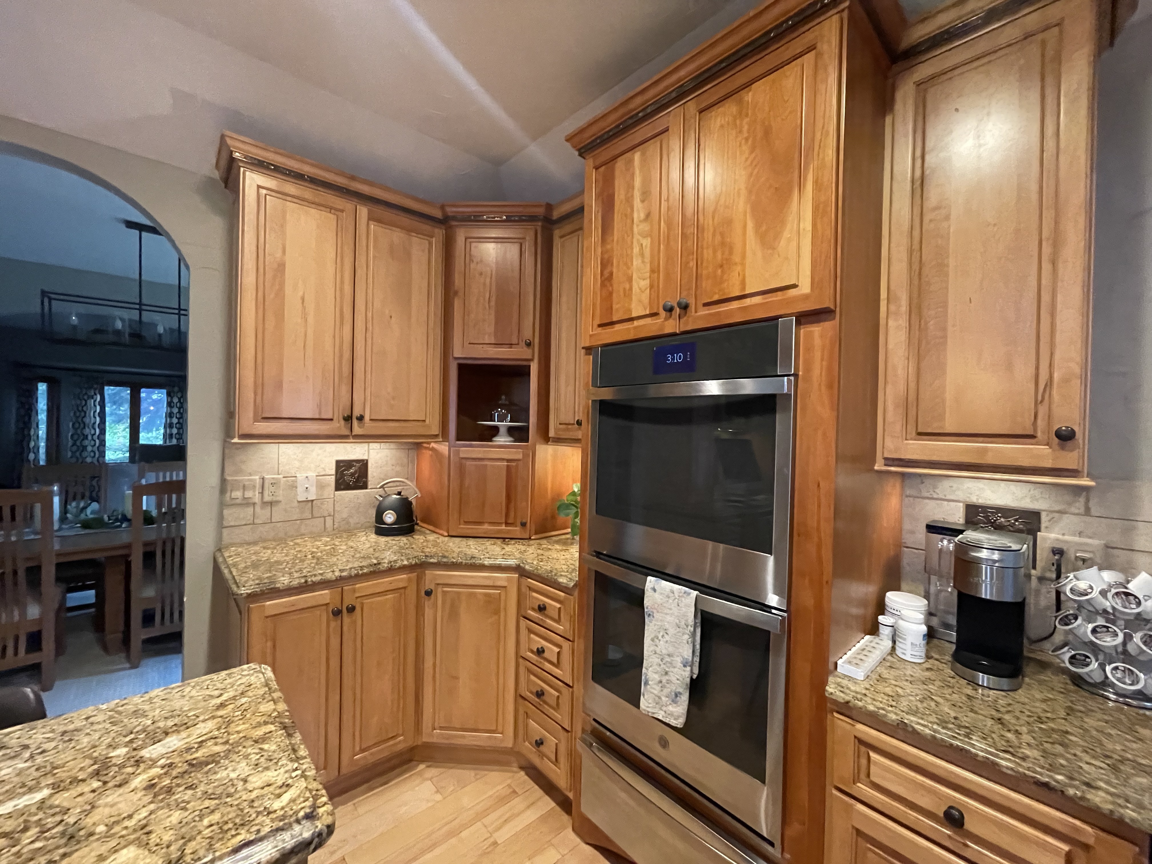 Traditional oak kitchen cabinets before DIY cabinet door replacement featuring raised panel cabinet doors, granite countertops, and built-in wall ovens prior to a modern Shaker kitchen remodel.