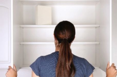 A person looking into empty cabinets.
