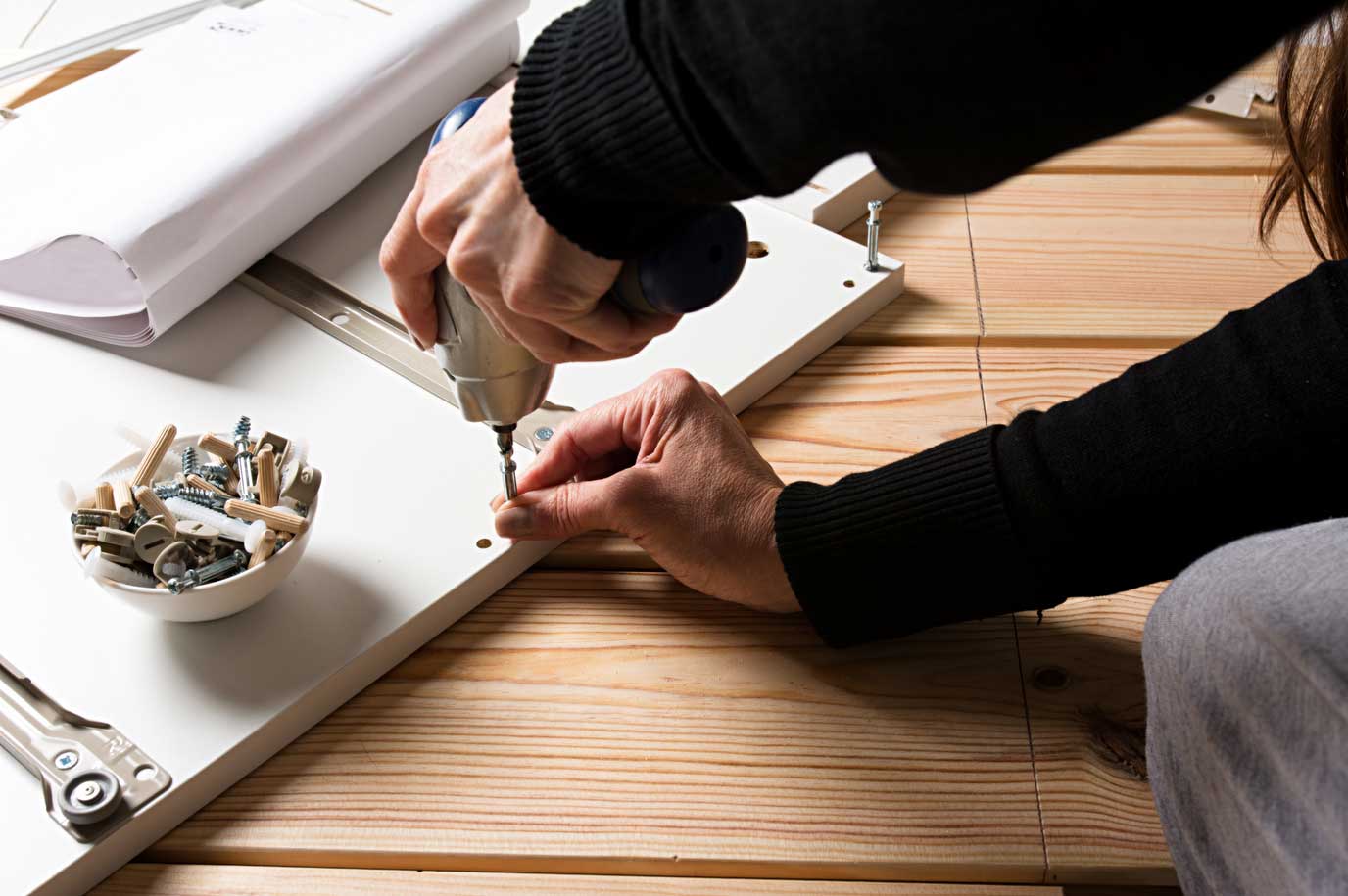 Person installing posts into a cabinet box for assembly.