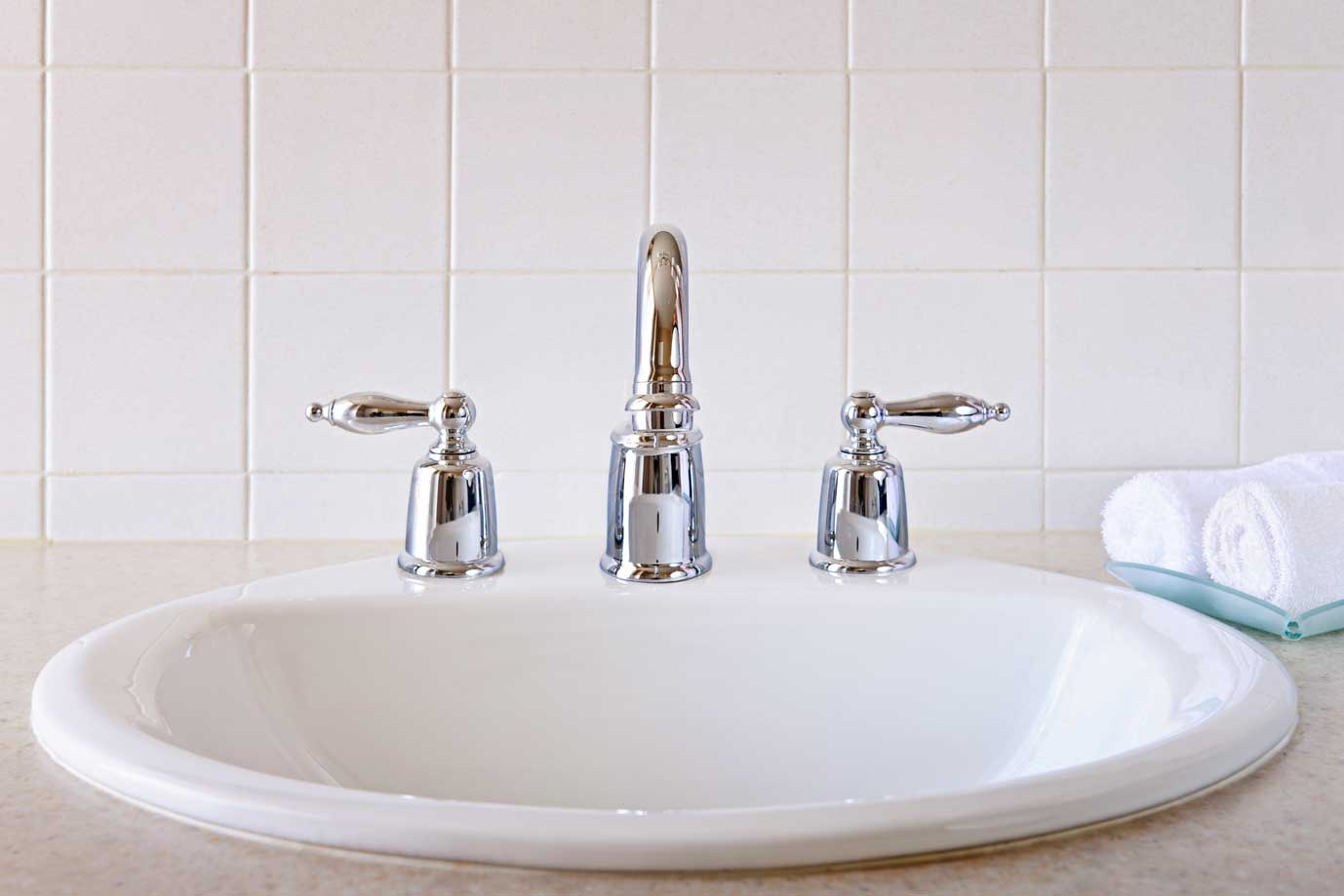 A white in-counter sink basin with silver fixtures.
