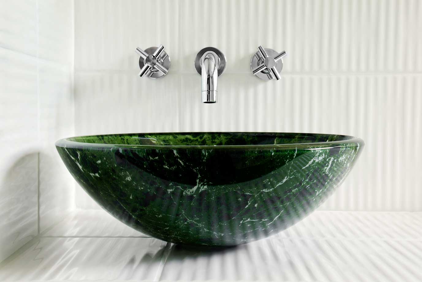 A green marble above counter sink basin with silver fixtures.