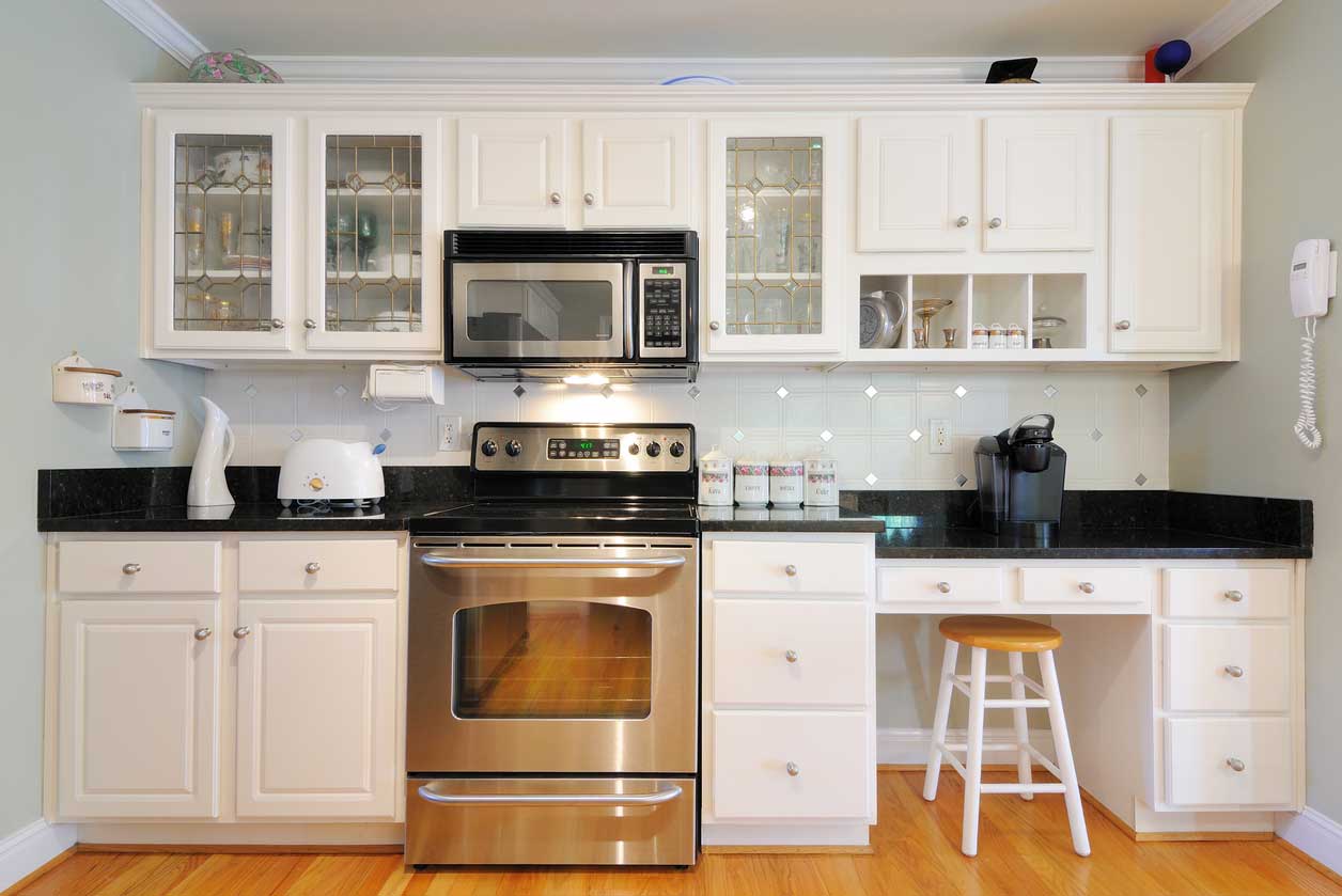 A galley kitchen with white cabinets and stainless steel appliances.