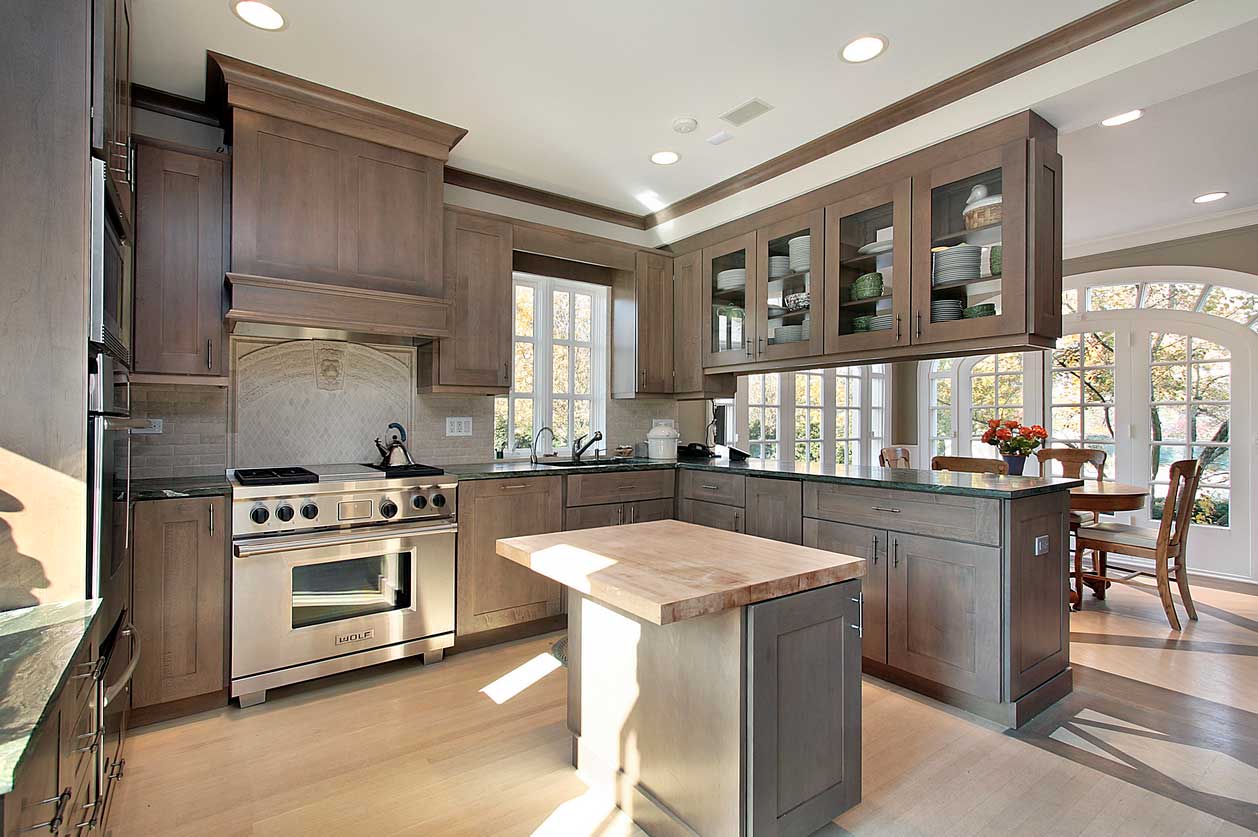 A U-shaped kitchen with island and glass-front shaker cabinets.