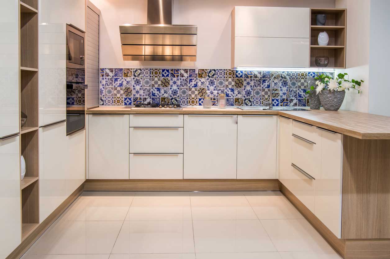 A white and light wood grain kitchen with a blue subway tile backsplash accent.