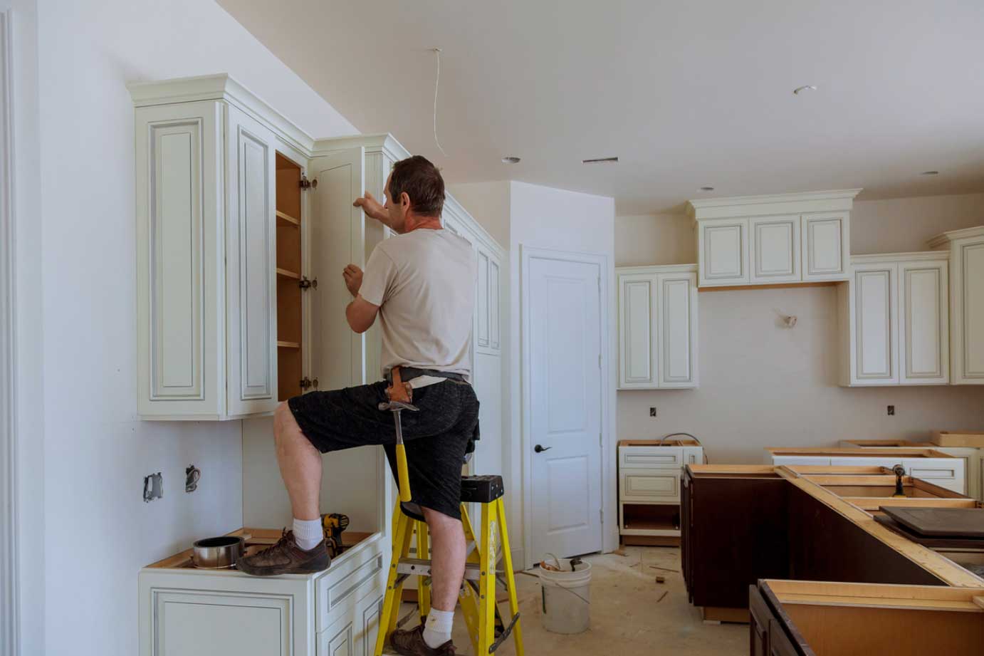 A person installing cabinet doors onto cabinet boxes.