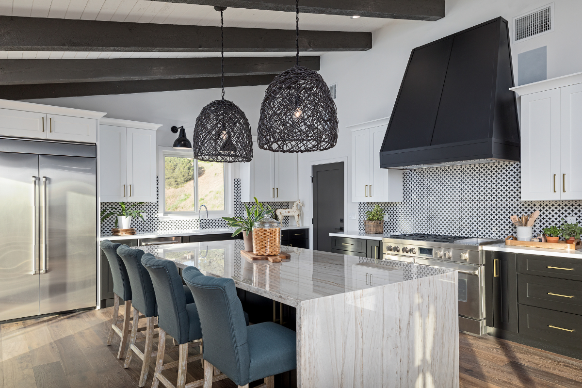 Modern kitchen featuring shaker cabinet doors with white upper cabinets and dark lower cabinets, large island, and contemporary lighting