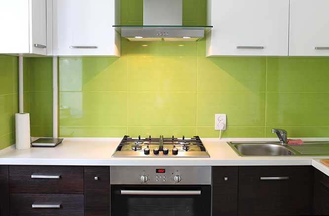 A two tone thermofoil kitchen with green tile backsplash.