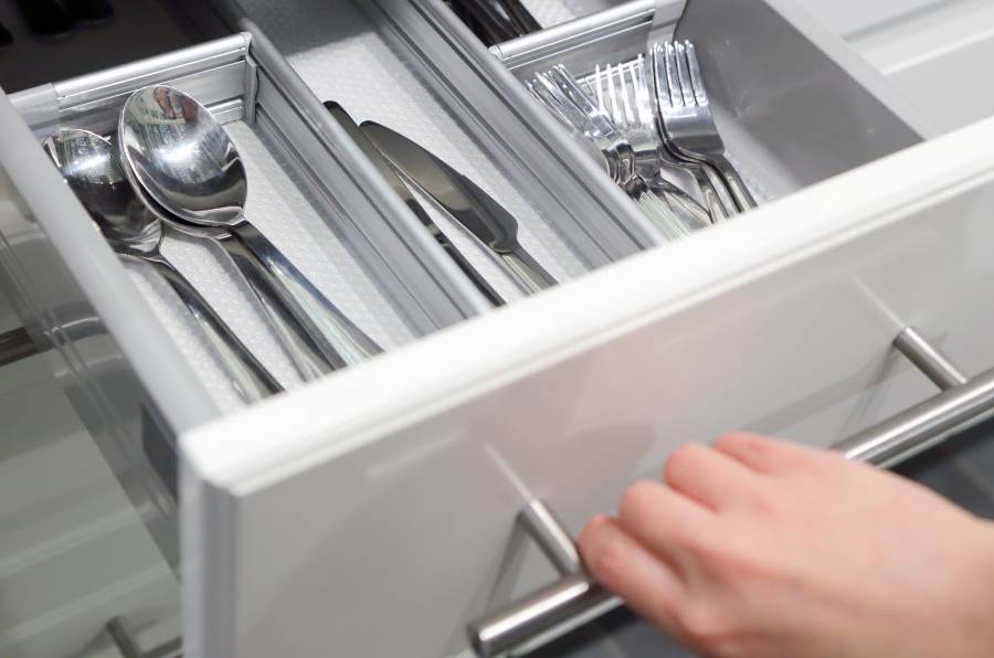 A person pulling open a utensils drawer.