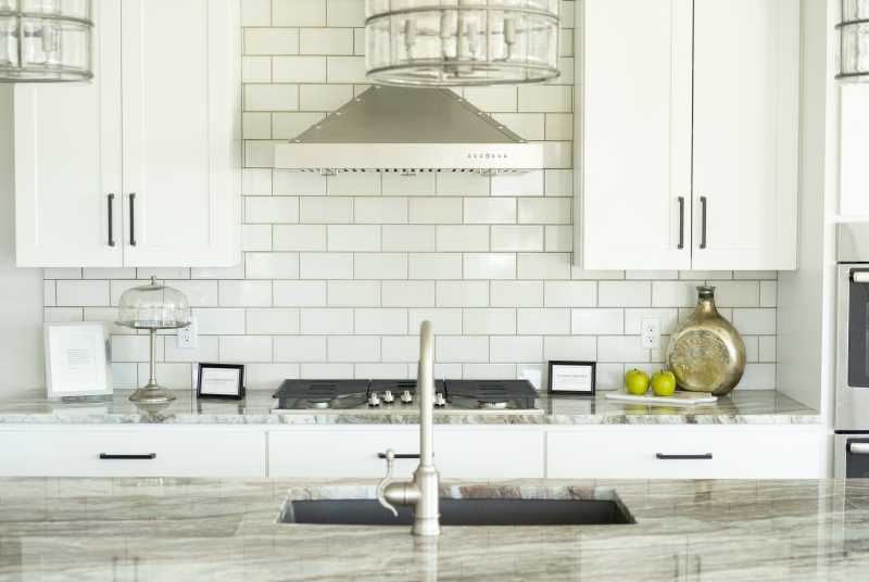 A kitchen with white cabinets and a subway tile backsplash.