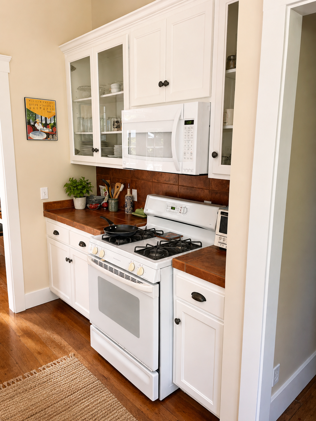 White Shaker Cabinet Doors and Glass Cabinets in a Cottage Kitchen White shaker cabinet doors and glass-front upper cabinets in Chris's cottage kitchen with warm wood floors and classic tile countertops.
